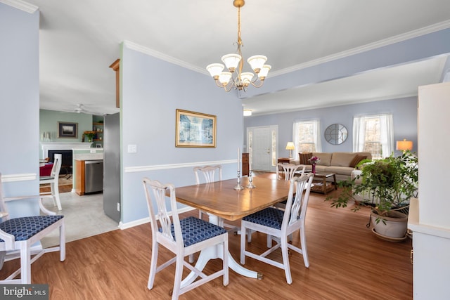 dining space featuring ceiling fan with notable chandelier, crown molding, wood finished floors, and baseboards