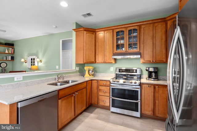 kitchen with visible vents, a sink, stainless steel appliances, under cabinet range hood, and brown cabinets