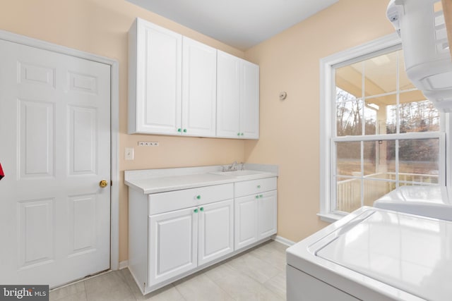 laundry area with a sink, baseboards, cabinet space, and independent washer and dryer