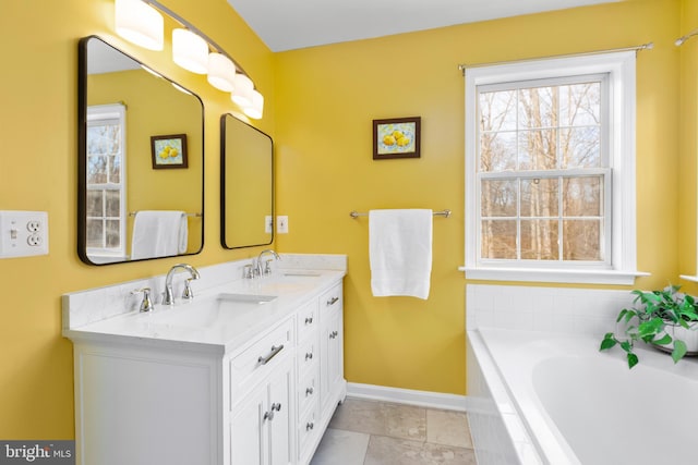 bathroom with double vanity, baseboards, tiled tub, and a sink