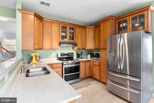 kitchen with visible vents, a sink, under cabinet range hood, appliances with stainless steel finishes, and glass insert cabinets