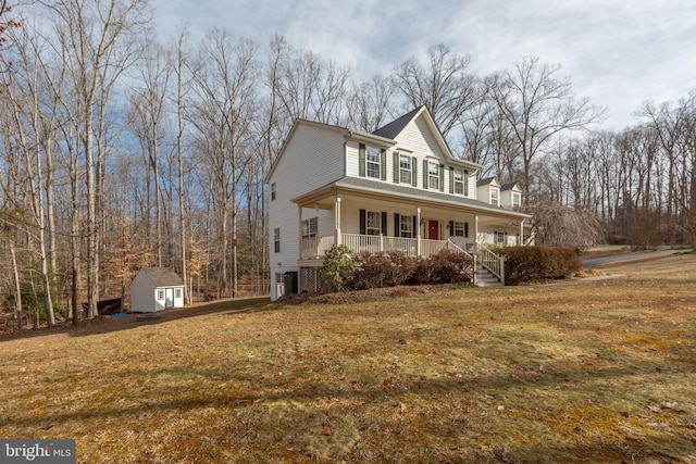 view of front of property featuring a shed, covered porch, a front yard, and an outdoor structure