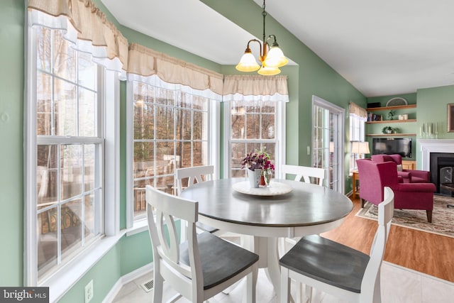 dining room featuring an inviting chandelier, wood finished floors, a healthy amount of sunlight, and visible vents