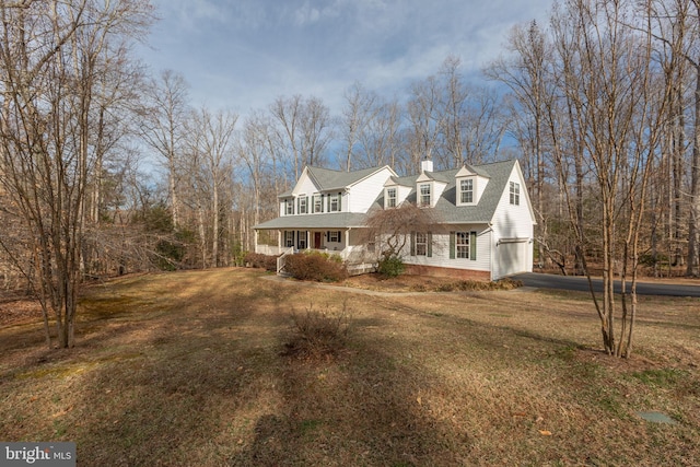 view of front of home featuring covered porch, a chimney, a front lawn, a garage, and aphalt driveway