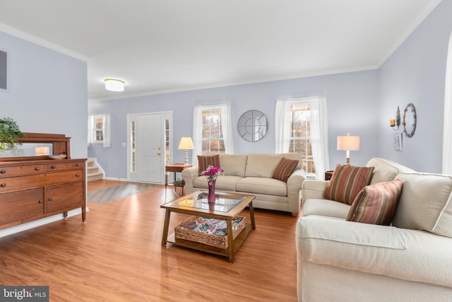 living area with stairs, light wood-style floors, and ornamental molding