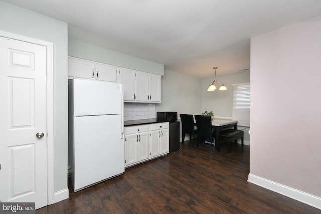 kitchen with a chandelier, freestanding refrigerator, white cabinets, and dark wood finished floors