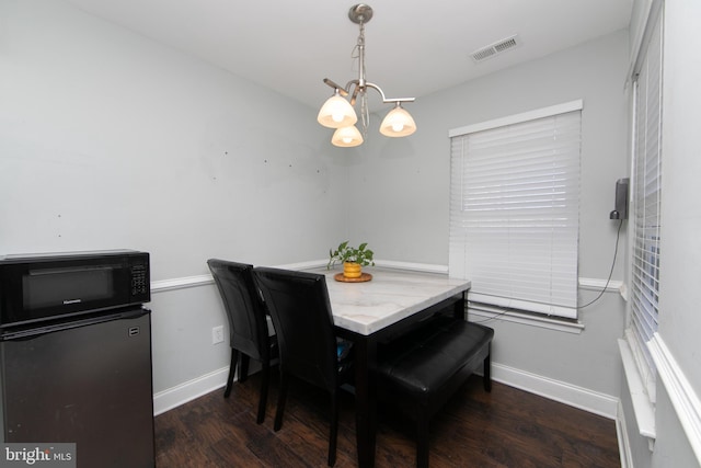 dining room featuring baseboards, wood finished floors, visible vents, and an inviting chandelier