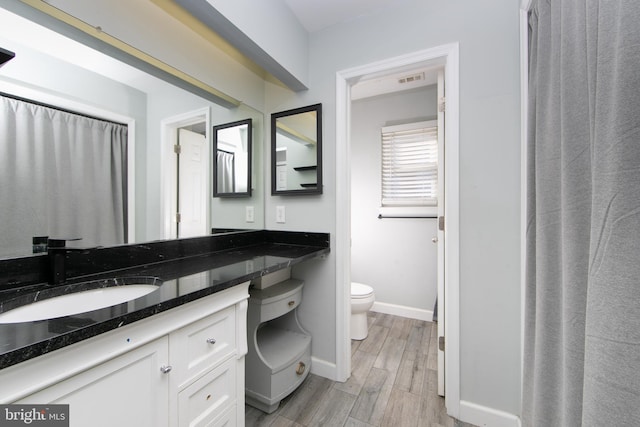 full bathroom with toilet, wood finish floors, visible vents, vanity, and baseboards