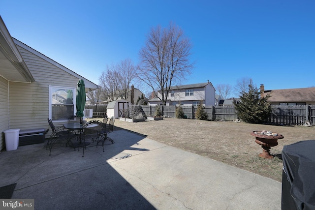 view of patio / terrace featuring an outbuilding, outdoor dining area, a fenced backyard, and a shed