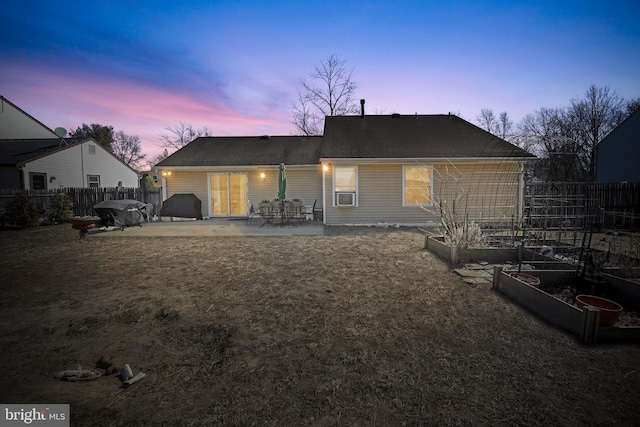 rear view of property featuring a patio area, a vegetable garden, a lawn, and fence