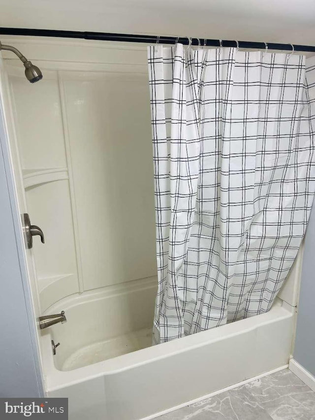 full bath featuring marble finish floor and shower / tub combo