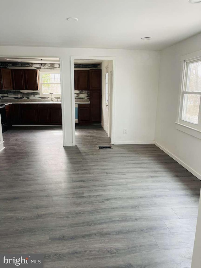 interior space with dark wood-type flooring, a sink, visible vents, and baseboards