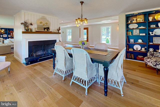 dining area featuring a chandelier, a fireplace, and wood finished floors