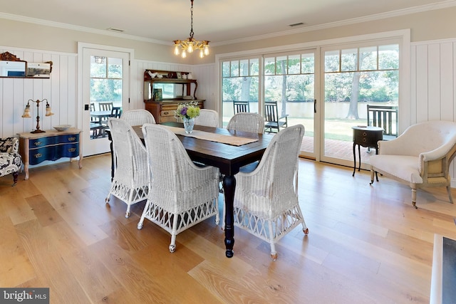 dining area featuring crown molding, an inviting chandelier, visible vents, and light wood-style floors