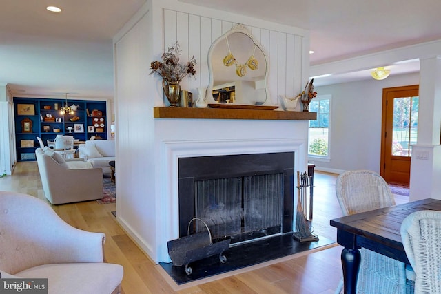 living area with a fireplace with flush hearth, recessed lighting, wood finished floors, and baseboards