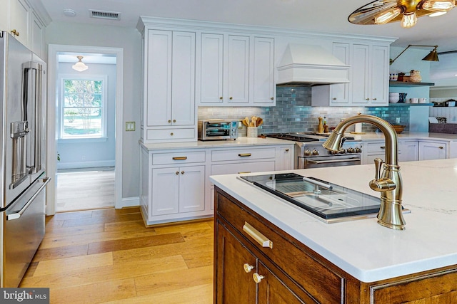 kitchen featuring premium range hood, premium appliances, visible vents, and white cabinets