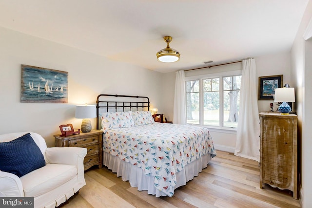 bedroom with light wood-type flooring, visible vents, and baseboards