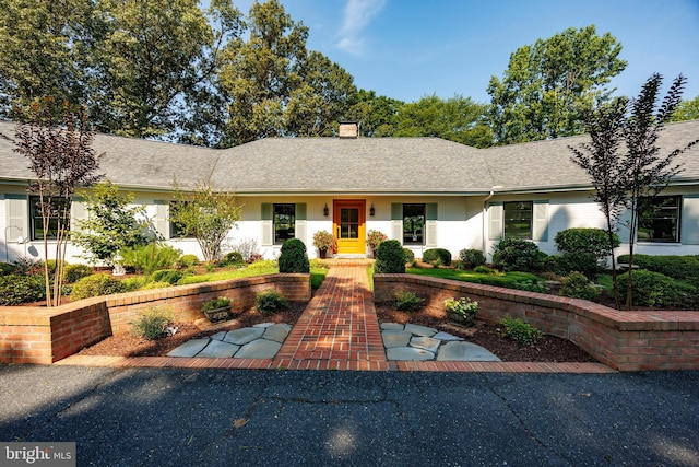 ranch-style house featuring a shingled roof and a chimney