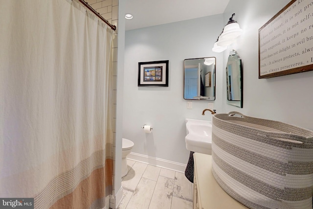 bathroom with wood finished floors, toilet, and baseboards