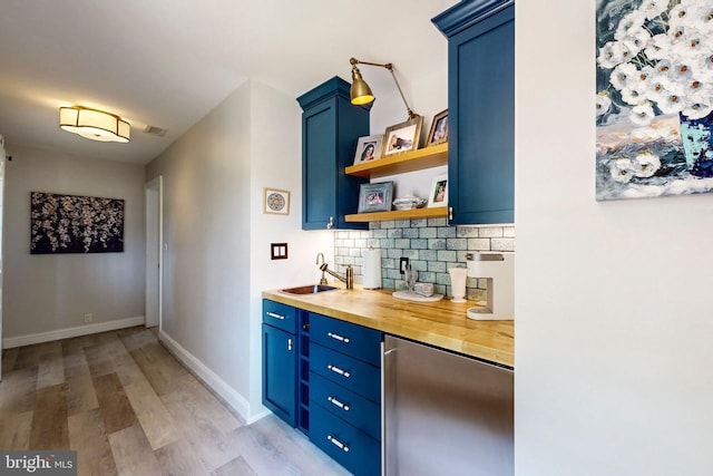 bar with refrigerator, a sink, visible vents, light wood-type flooring, and backsplash