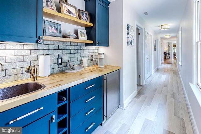 interior space featuring baseboards, light wood-style flooring, visible vents, and a sink