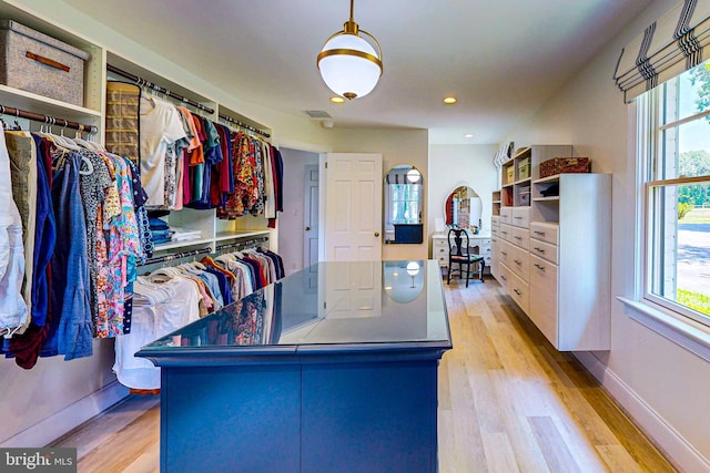 walk in closet with arched walkways and light wood finished floors