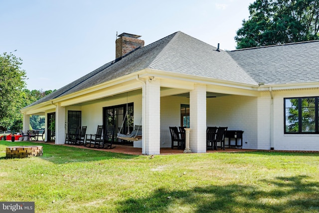 back of house featuring a shingled roof, brick siding, and a lawn