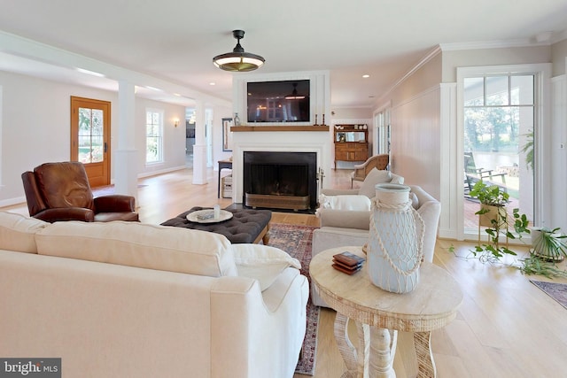 living room featuring a fireplace with flush hearth, recessed lighting, ornamental molding, and light wood-style flooring