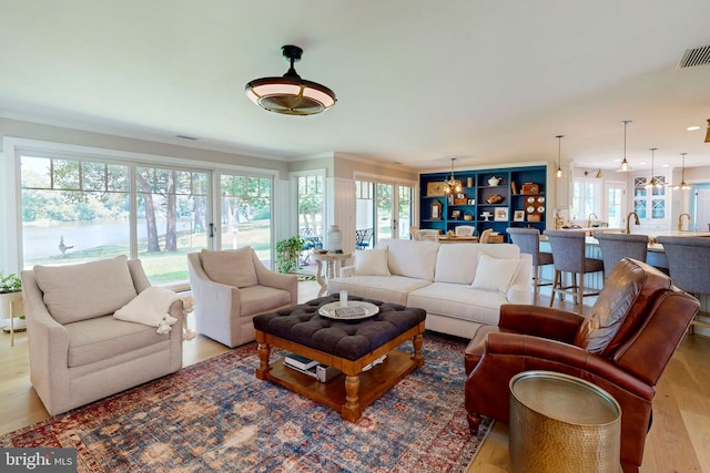 living area featuring ornamental molding, visible vents, and wood finished floors