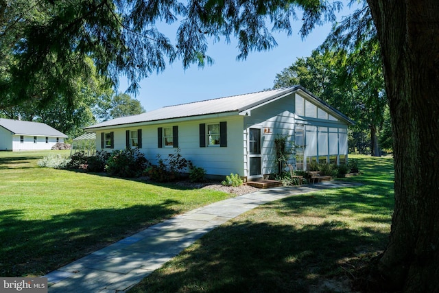 ranch-style home with a front yard and metal roof