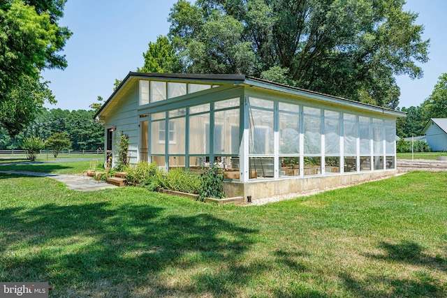 view of property exterior featuring a sunroom and a yard