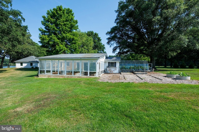 back of house featuring an outbuilding, a garden, and a lawn