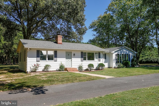 single story home with a front lawn, a chimney, and a shingled roof