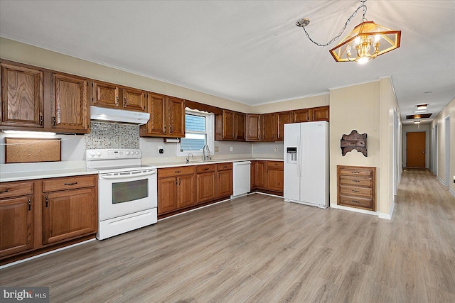 kitchen featuring under cabinet range hood, white appliances, light countertops, and light wood finished floors