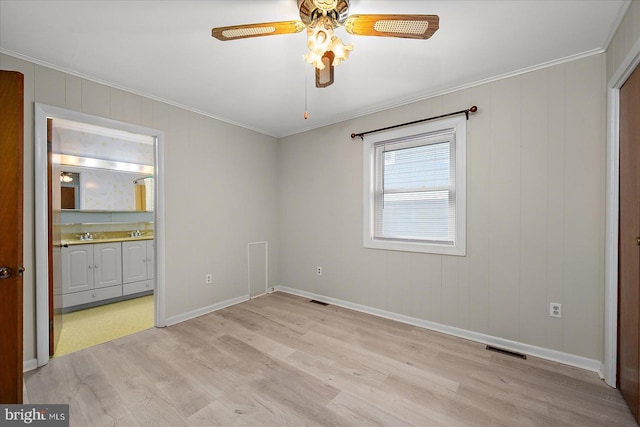 empty room with light wood-type flooring, visible vents, ornamental molding, a ceiling fan, and baseboards