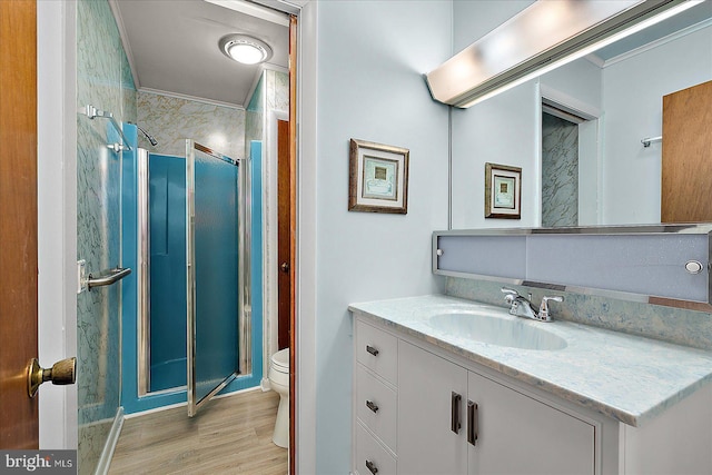 bathroom with vanity, wood finished floors, a stall shower, crown molding, and toilet