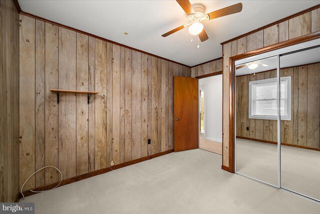 unfurnished bedroom featuring a closet, baseboards, wood walls, and carpet floors