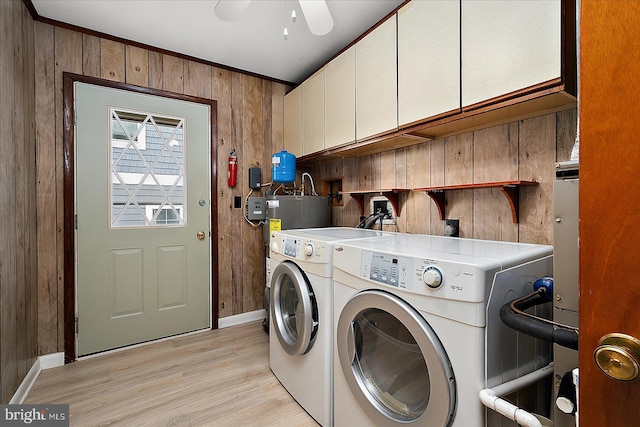 washroom with wooden walls, water heater, light wood-style flooring, cabinet space, and independent washer and dryer