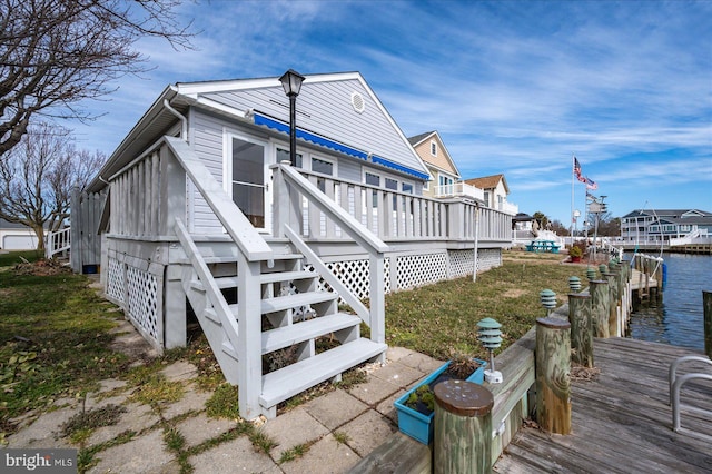 view of home's exterior featuring stairs, a deck with water view, and a dock