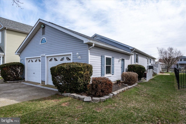 view of side of property with concrete driveway, a yard, fence, and an attached garage