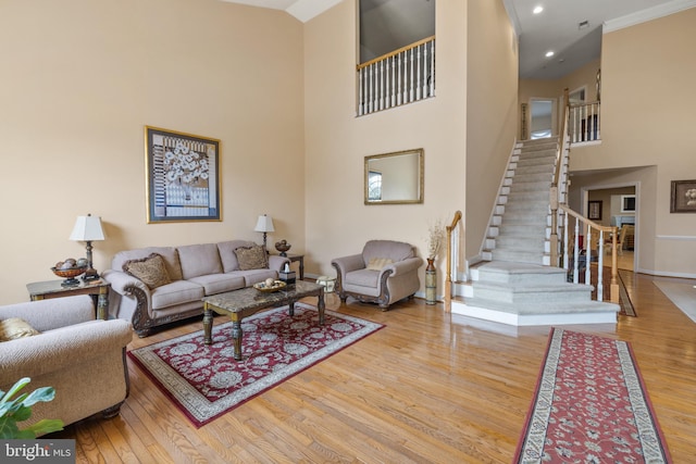 living area featuring stairs, a high ceiling, wood finished floors, and recessed lighting