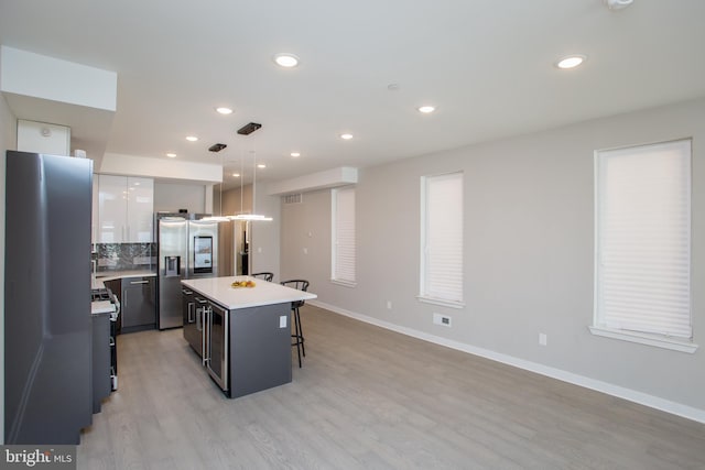 kitchen with a breakfast bar, a center island, pendant lighting, tasteful backsplash, and stainless steel fridge with ice dispenser