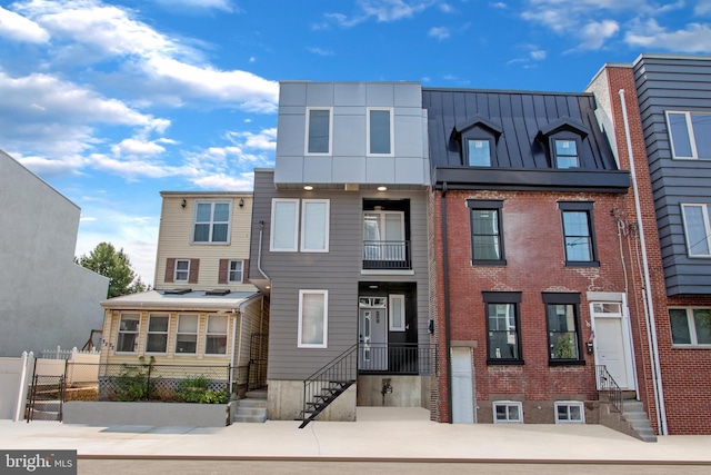 view of property featuring entry steps, a standing seam roof, metal roof, and brick siding