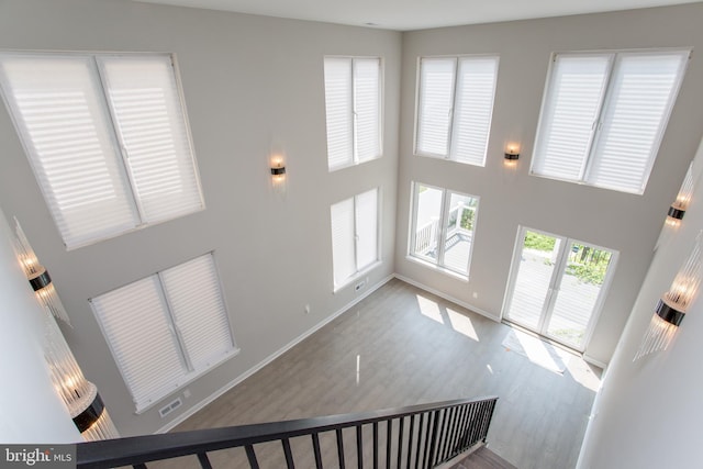 stairs featuring a high ceiling, wood finished floors, visible vents, and baseboards