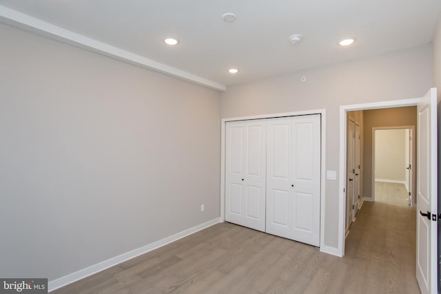 unfurnished bedroom with light wood-style flooring, baseboards, a closet, and recessed lighting