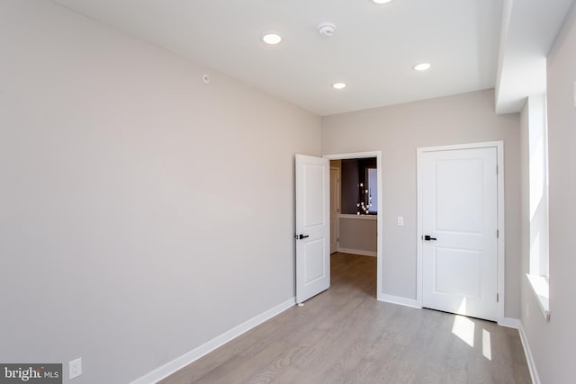 unfurnished bedroom with recessed lighting, light wood finished floors, and baseboards