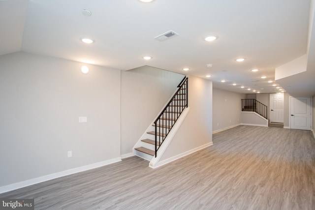 finished below grade area featuring stairs, recessed lighting, light wood-style flooring, and baseboards