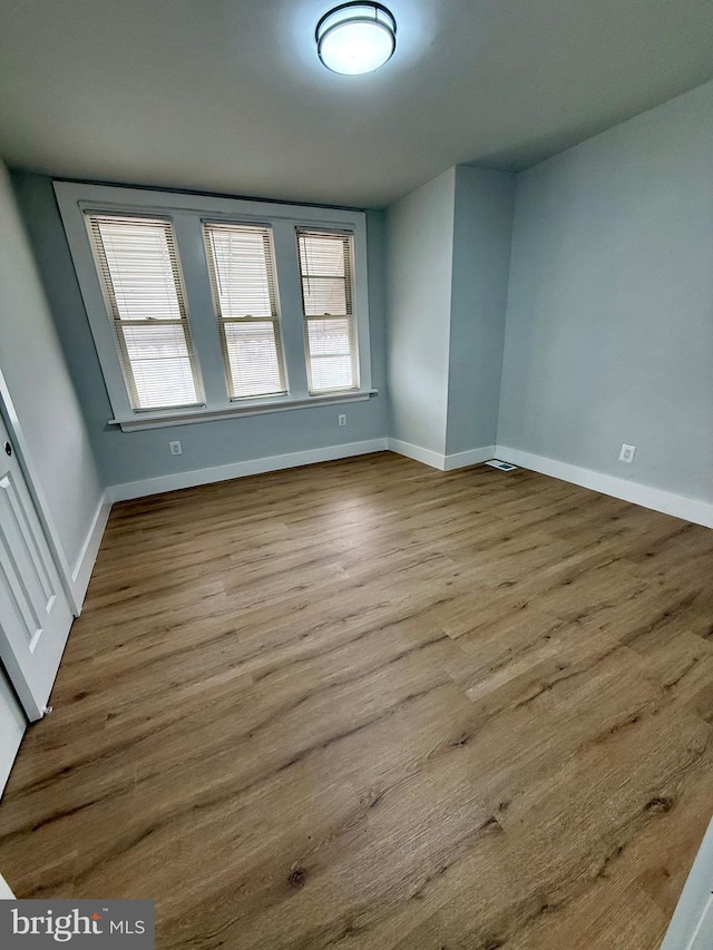 unfurnished room featuring a healthy amount of sunlight, baseboards, and wood finished floors