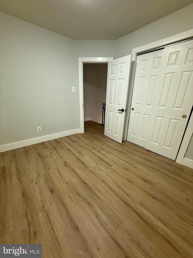 unfurnished bedroom featuring a closet, wood finished floors, and baseboards