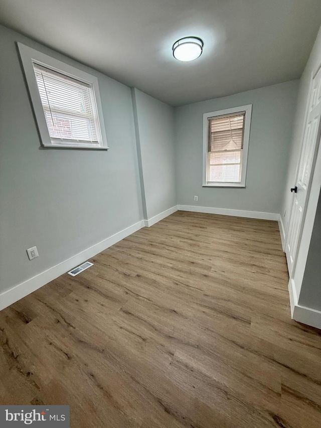 unfurnished bedroom featuring baseboards, visible vents, and wood finished floors